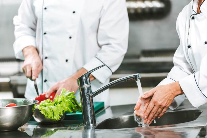 A food handler wets hands and arms applies liquid soap