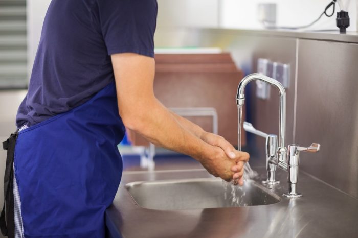 A food handler wets hands and arms applies liquid soap